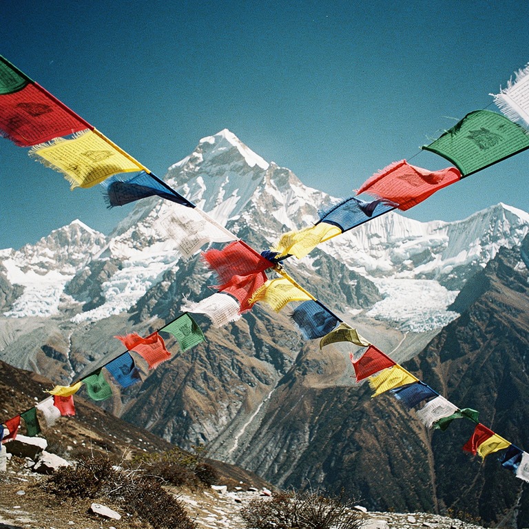 Prayer flags fluttering against a Himalayan peak | ShopAyahuascaRetreats