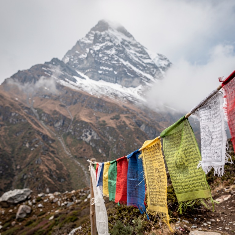 Prayer flags fluttering against a Himalayan peak | ShopAyahuascaRetreats