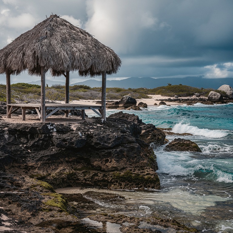 A palapa with a thatched roof stands alone on a rocky shorel... | ShopAyahuascaRetreats