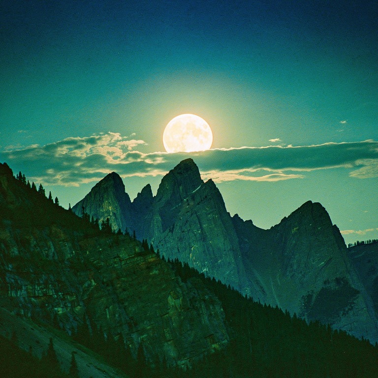 Full moon rising behind silhouetted mountain peaks | ShopAyahuascaRetreats