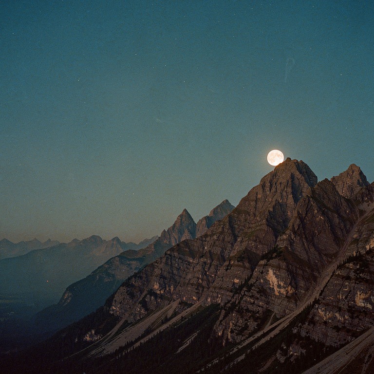 Full moon rising behind silhouetted mountain peaks | ShopAyahuascaRetreats
