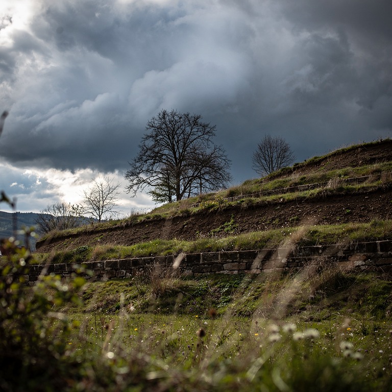 A dramatic storm cloud gathers over a terraced hillside in r... | ShopAyahuascaRetreats